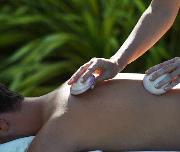 Ganzkörpermassage mit warmen Muscheln und fließenden Griffen zur Lösung von Verspannungen und Förderung des Wohlbefindens.