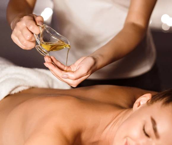 Therapist holds soothing massage oil over the back for a relaxing Thai oil massage.