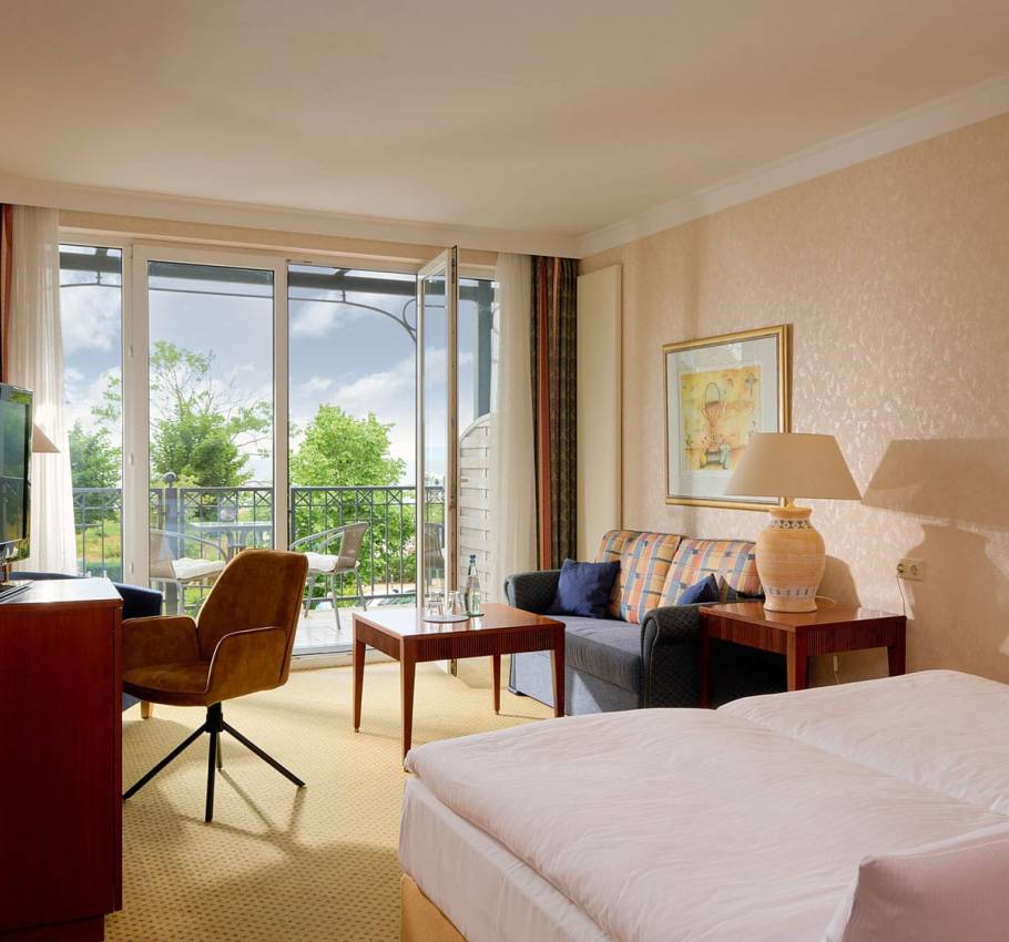 Komfortables Baltic Deluxe Zimmer im Grand Hotel Binz mit gemütlicher Sitzecke, Balkon und Ostseepanorama.