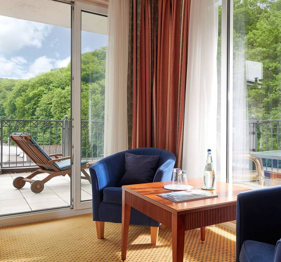 Elegantes Granitz Deluxe Zimmer im Grand Hotel Binz mit Dachterrasse, Loungemöbeln und Blick ins Grüne.