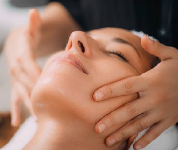 A woman enjoys the pleasant relaxation of a facial massage.