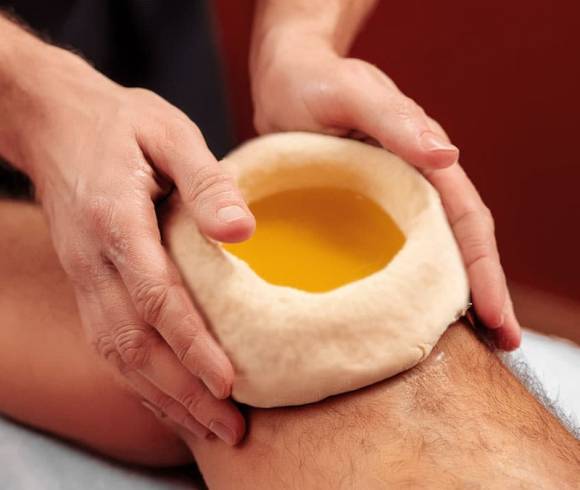 Ayurvedic dough ring on one knee, filled with soothing herbal oil.
