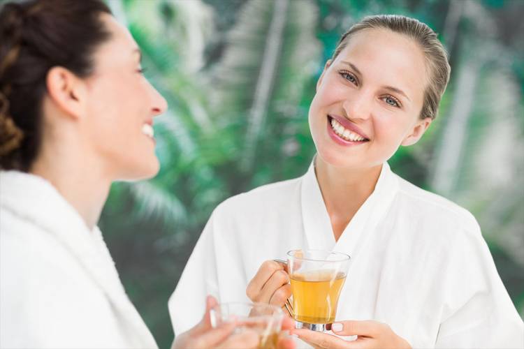 Zwei glückliche Frauen mit entschlackendem Tee beim Fastenurlaub im Grand Hotel Binz auf Rügen.