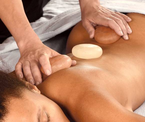 Wellness treatment with Himalayan salt stones on the back for muscle relaxation.