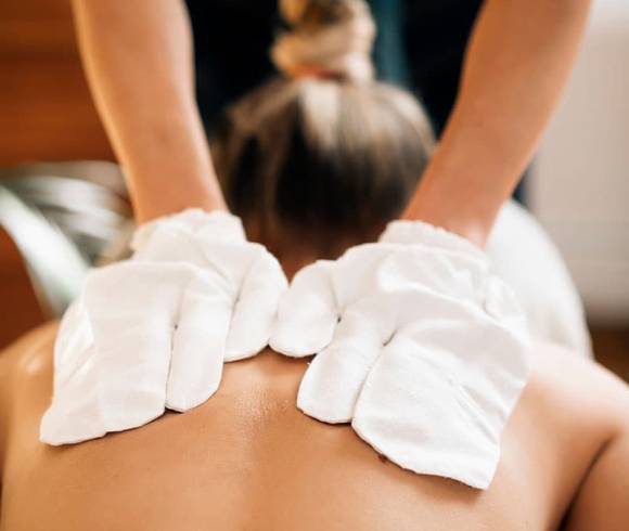 A woman receives a back massage with original Ayurvedic silk gloves.