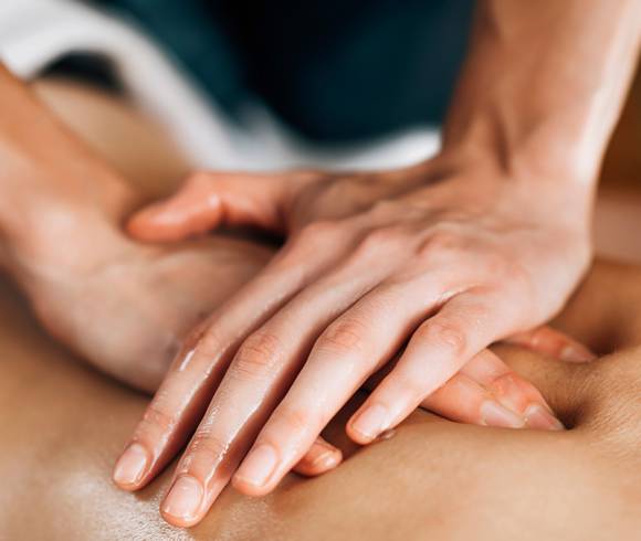Hands placed on top of each other exerting gentle pressure during an Ayurvedic massage.