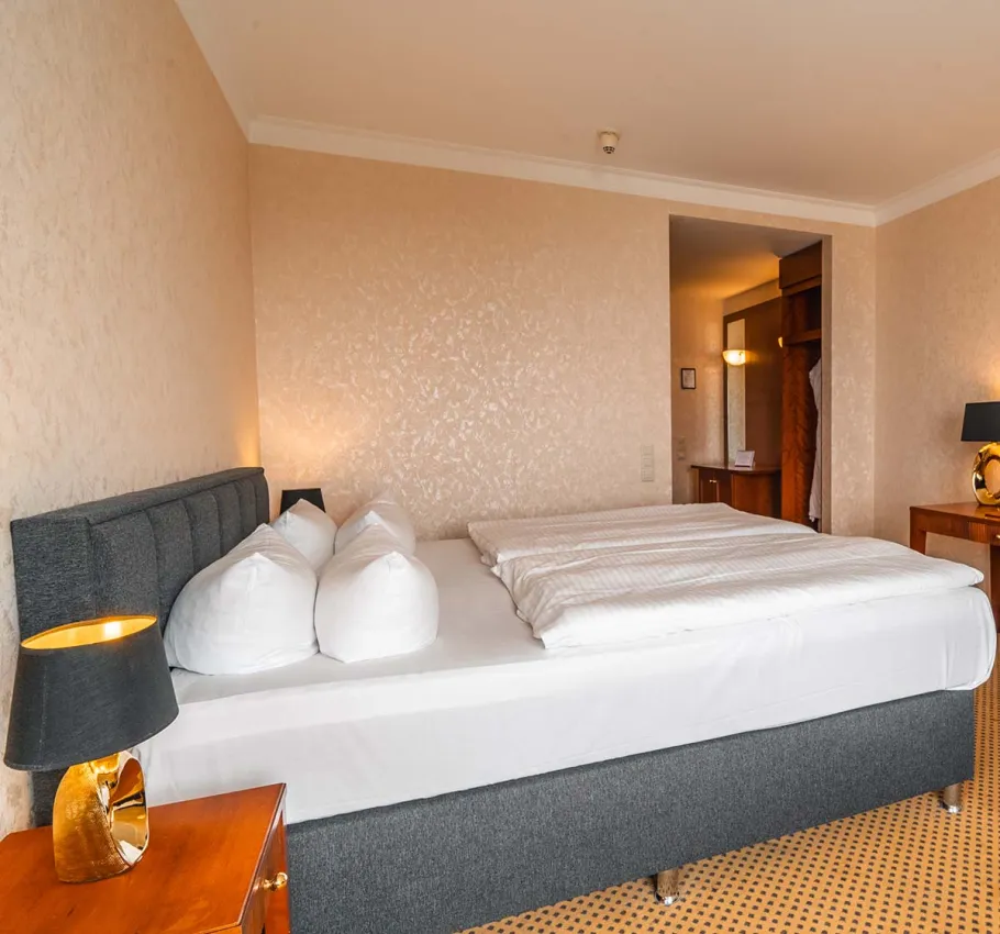 Stilvolles Doppelbett und umfangreiche Zimmerausstattung im Baltic Deluxe Dachterrassen-Hotelzimmer.