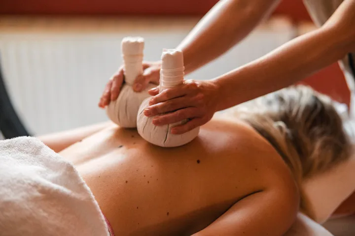 A female guest receives a herbal stamp massage based on Ayurvedic tradition at the hotel spa.