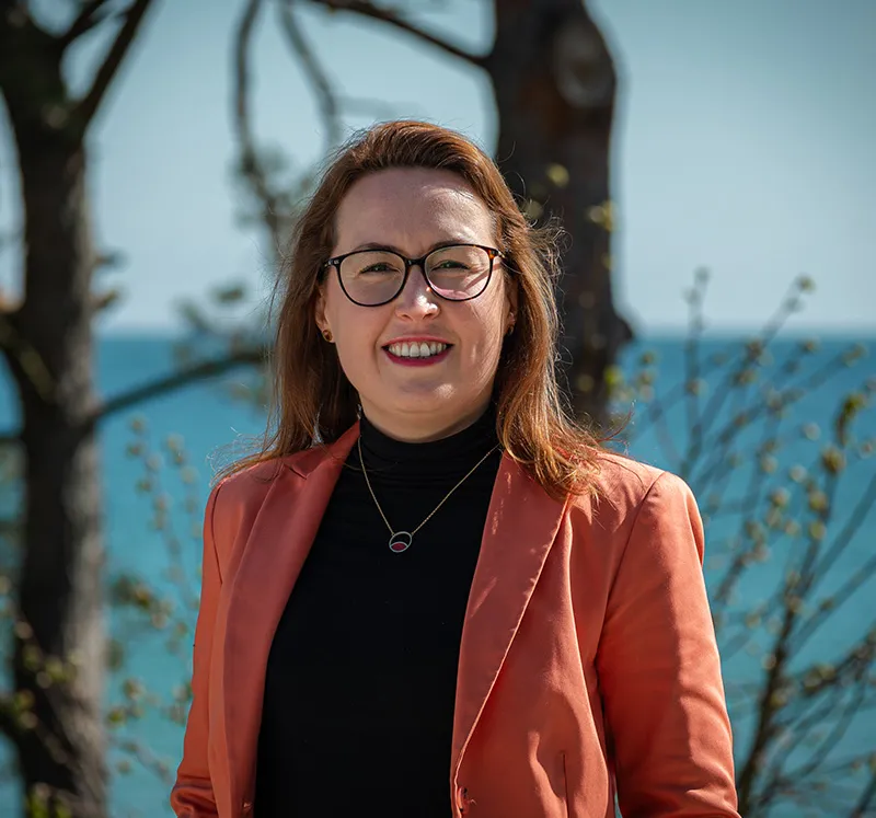 Portrait picture of management assistant Dorothee Schicht in front of the Baltic Sea, who helps with press and cooperation issues at Arkona Hotels.