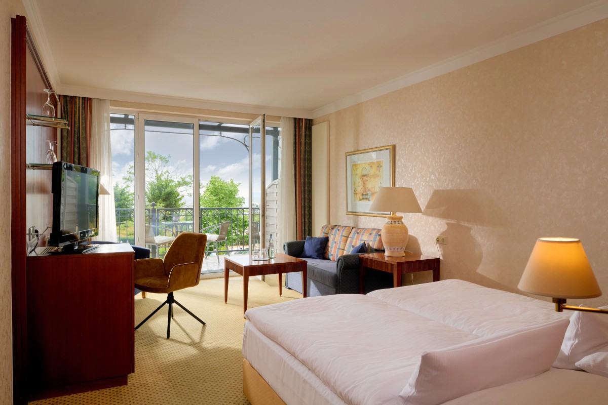 Helles Hotelzimmer zum Entspannen mit gemütlichem Doppelbett und Blick in die Natur im Grand Hotel Binz.