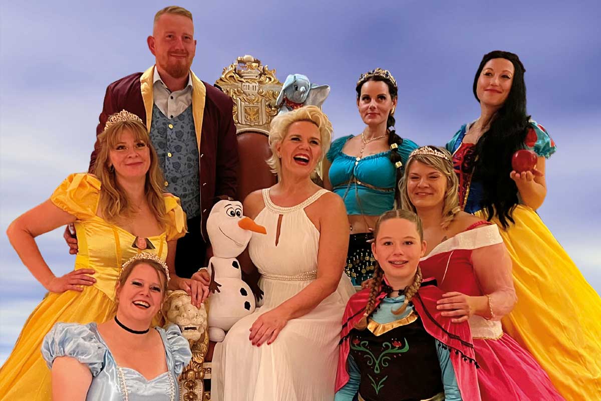 Nicole Mühle umgeben von Darstellern in Disney-Kostümen bereit für den Disney-Abend im Arkona Strandhotel in Binz.