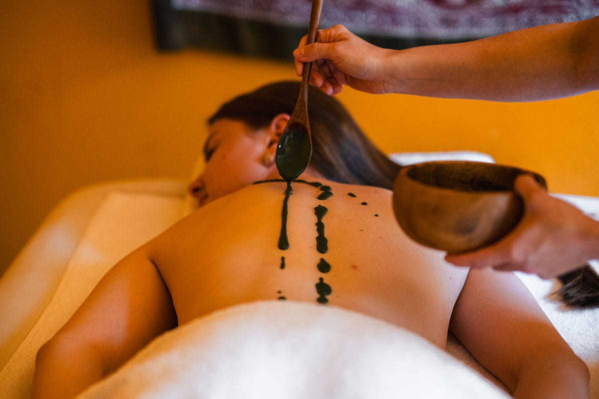 Wellnessanwendung mit naturreiner Algenpaste auf den Rücken einer Spa-Gästin